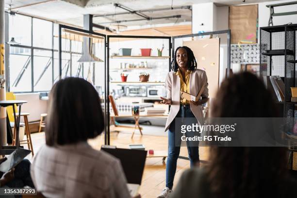 geschäftsfrau hält eine präsentation vor den frauen - african american speaking to an audience stock-fotos und bilder