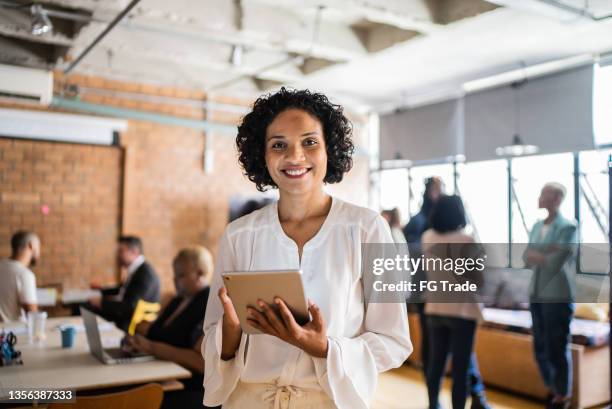 portrait of a business woman using digital tablet in the office - hispanic woman stockfoto's en -beelden