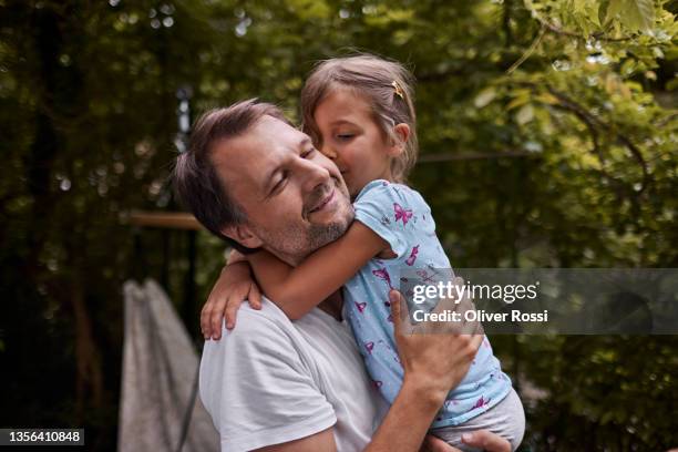 father and daughter hugging in garden - umarmen stock-fotos und bilder