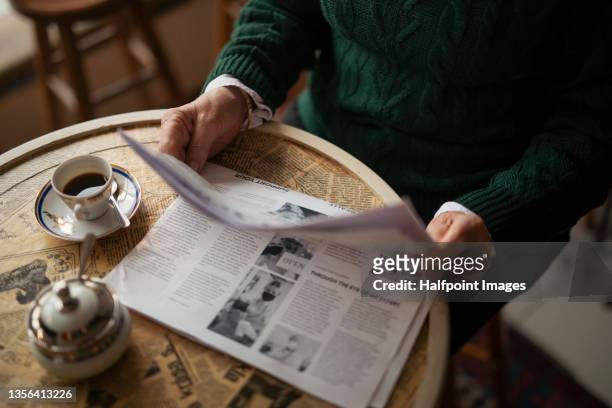 unrecognizable senior woman reading newspaper and having coffee indoors in café. - newspaper stock pictures, royalty-free photos & images