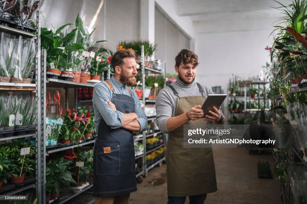 Using Technology In Small Business, Male Workers using digital tablet in flower warehouse.