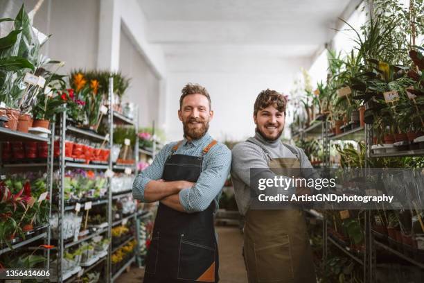 squadra allegra di fioristi maschi nel magazzino di giardinaggio - founder foto e immagini stock