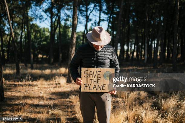 man in the woods holding a cardboard sign that says save the planet - vegan activist stock pictures, royalty-free photos & images
