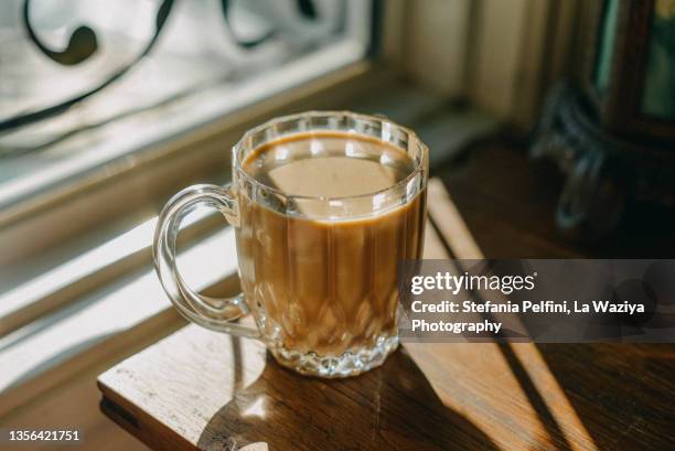 vegan caffe latte in a glass mug casting a shadow on a wooden table - chicoree stock-fotos und bilder