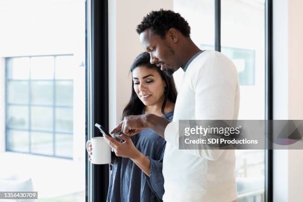 couple news on smartphone - mid adult men stock pictures, royalty-free photos & images
