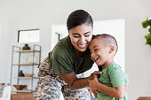 Soldier mom playfully tickles elementary age son
