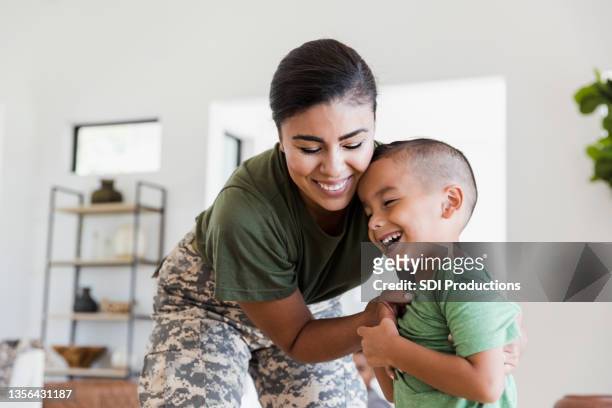 soldier mom playfully tickles elementary age son - armed forces stock pictures, royalty-free photos & images