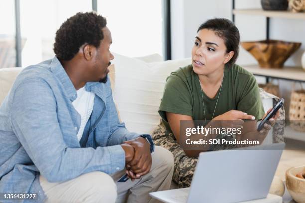 soldier wife shows husband something on smart phone - couple serious stock pictures, royalty-free photos & images