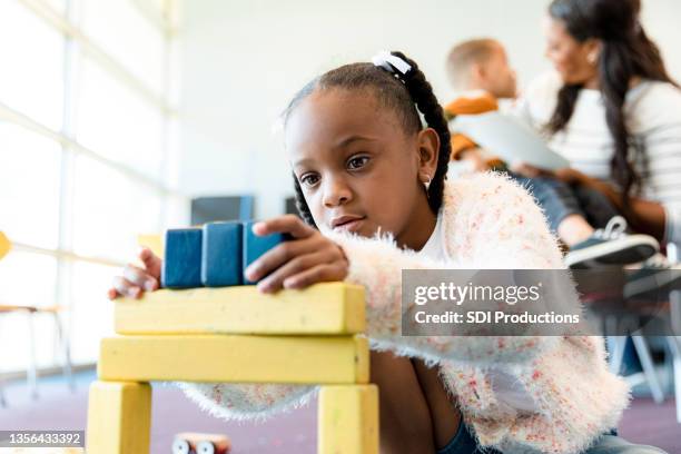 cute preschool girl sits on floor to play with blocks - public school building stock pictures, royalty-free photos & images