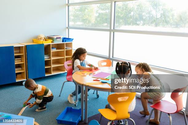 busy preschool children enjoy their time in daycare - daycare stock pictures, royalty-free photos & images