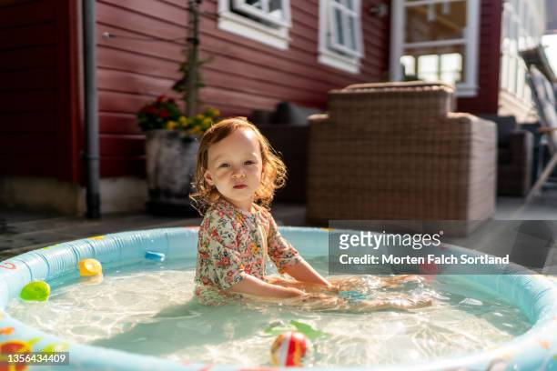 morning sunshine on a young girl in a pool - inflatable swimming pool stock pictures, royalty-free photos & images