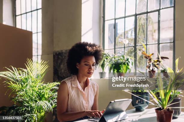 fiorista sorridente che lavora nel suo negozio di fiori - business sostenibile foto e immagini stock