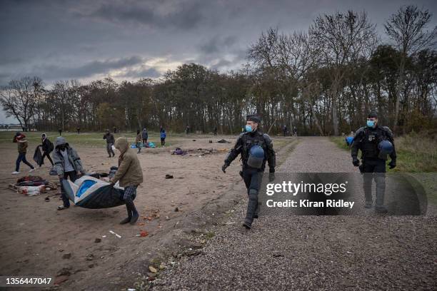 Police evict migrants from a makeshift camp at daybreak on the outskirts of Calais in the latest attempt to disperse migrants from gathering along...