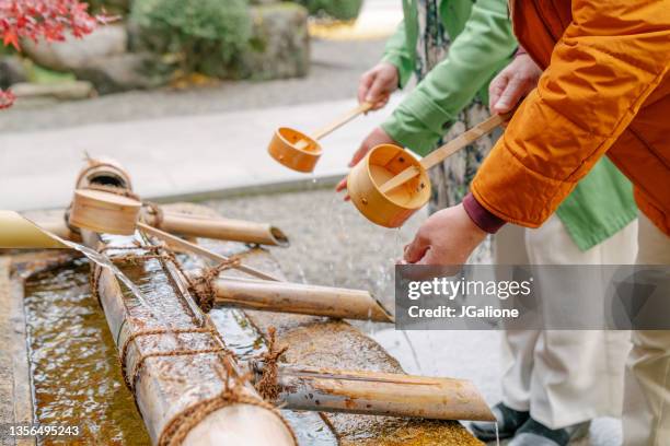 senior couple cleaning their hands at a japanese temple - shinto shrine stock pictures, royalty-free photos & images