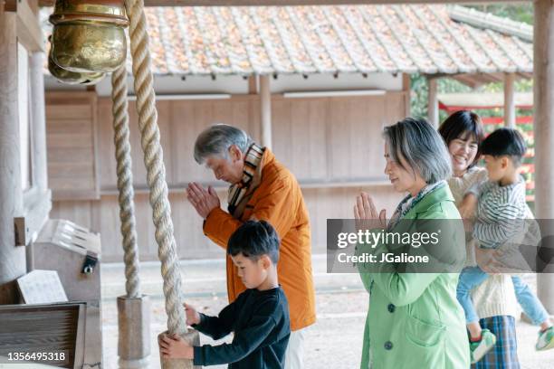 familia multigeneracional orando en un templo japonés - templo fotografías e imágenes de stock