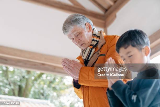 grandfather praying with his grandson at a japanese temple - shinto shrine stock pictures, royalty-free photos & images