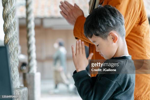 kleiner junge, der mit seinem großvater in einem japanischen tempel betet - shrine stock-fotos und bilder