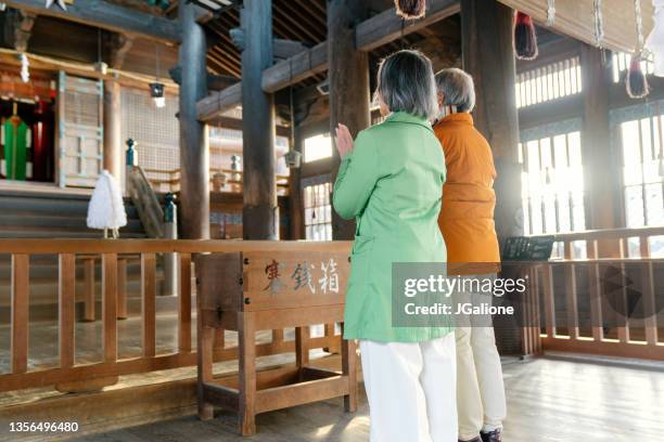 senior couple praying a japanese temple for hatsumode - godsdienstige gebouwen stockfoto's en -beelden