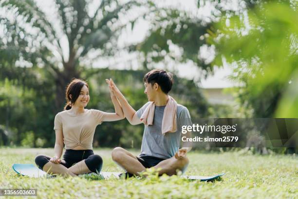 full length shot of a young asian couple doing yoga at outdoor public park - asian young couple stock pictures, royalty-free photos & images