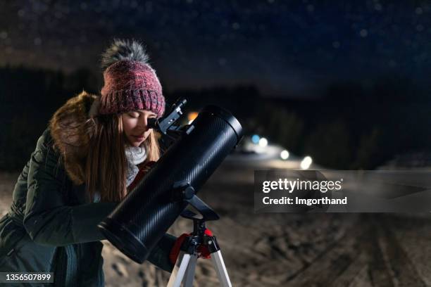 ragazza adolescente che osserva il cielo notturno invernale con il telescopio - see through foto e immagini stock