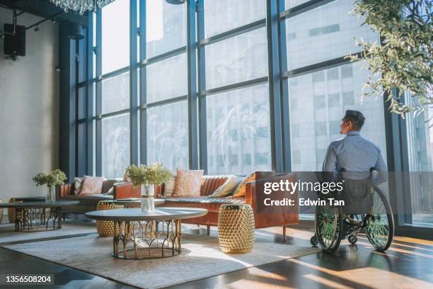 rear view disable asian indian male white collar worker in wheelchair looking away at lobby lounge area - back cushion stock pictures, royalty-free photos & images