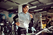 Determined athletic woman running on treadmill while practicing in a gym.