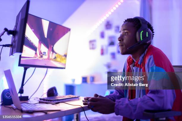 young male gamer playing at night - video game stock-fotos und bilder