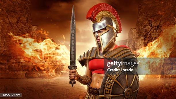 eine weibliche krieger-gladiatorin, die eine waffe in einer arena hält - traditionelle rüstung stock-fotos und bilder