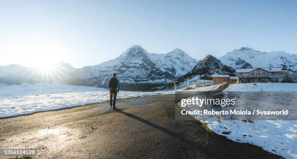 hiker walking on empty road to eiger mount, switzerland - grindelwald switzerland stock pictures, royalty-free photos & images