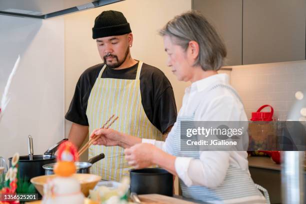 senior woman teaching her adult son how to cook - traditional piercings stock pictures, royalty-free photos & images