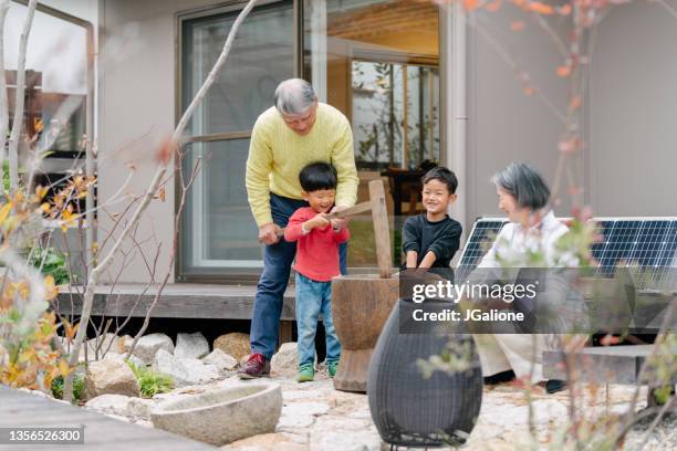 grandparents teaching their grandchildren how to make traditional new years mochi - new year japan stock pictures, royalty-free photos & images