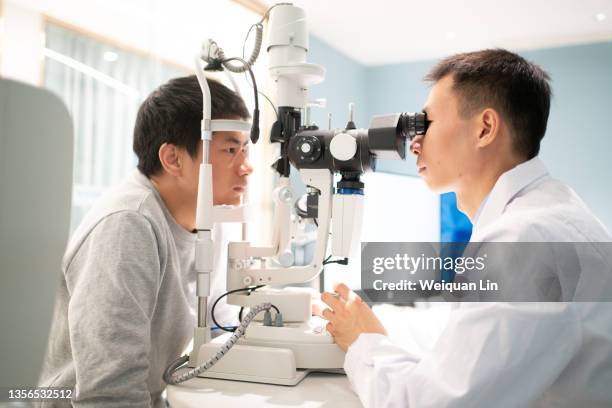 the ophthalmologist is examining the eyes of the patient - ophthalmologist fotografías e imágenes de stock