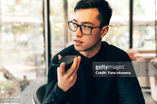 smart and handsome asian entrepreneur is using mobile phone to record an audio message - message sms ストックフォトと画像