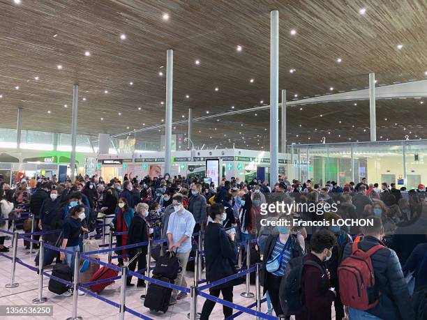 Foule de voyageurs masqués avec leurs bagages faisant la queue aux guichets d'enregistrement de l'aéroport Roissy Charles de Gaulle le 28 octobre...