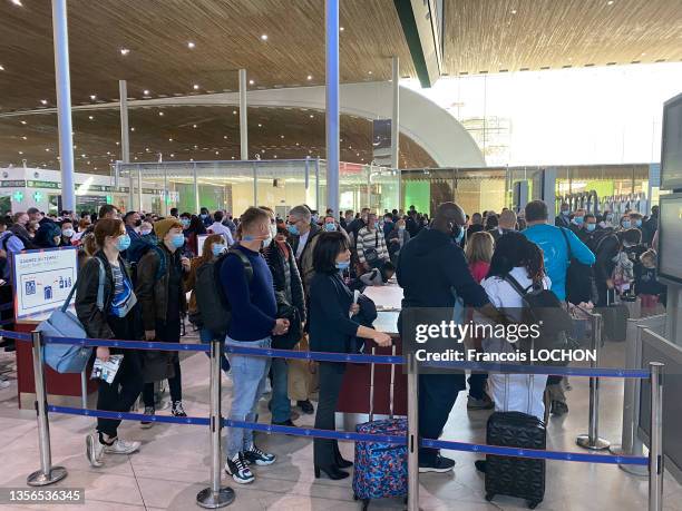 Foule de voyageurs masqués avec leurs bagages faisant la queue aux guichets d'enregistrement de l'aéroport Roissy Charles de Gaulle le 28 octobre...