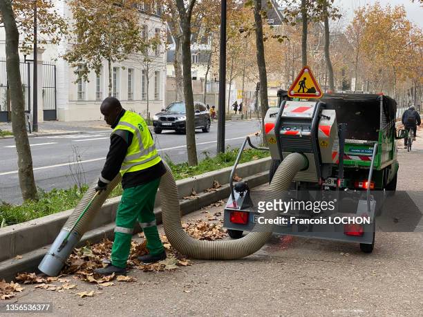 Un agent d'entretien aspire les feuilles d'automne tombées sur la chaussée le 19 novembre 2021 à Paris.