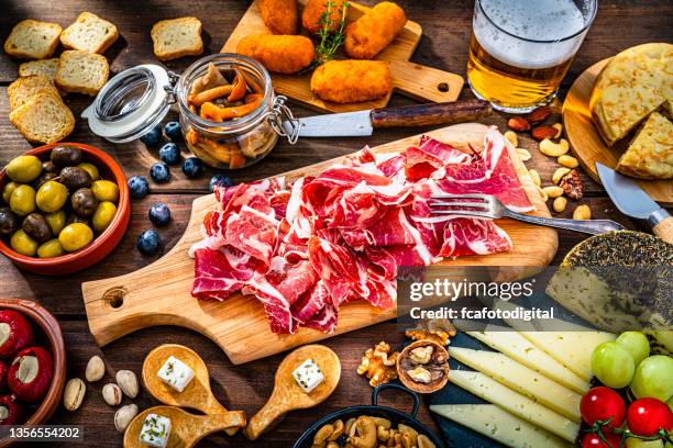 jamón serrano y cerveza sobre mesa de madera - jamón serrano fotografías e imágenes de stock