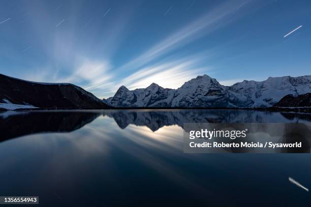 star trail over eiger peak reflected in engital lake, switzerland - eiger mönch jungfrau stockfoto's en -beelden