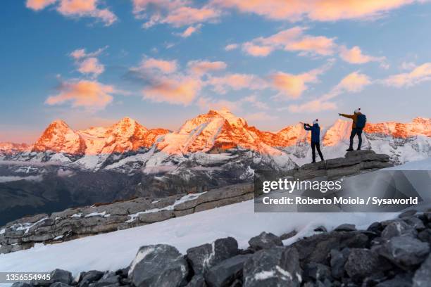 two people watching sunset over eiger and monch peaks - eiger stock pictures, royalty-free photos & images