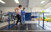 Woman in physical therapy walking on the parallel bars