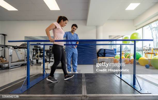 woman in physical therapy walking on the parallel bars - women injury bildbanksfoton och bilder