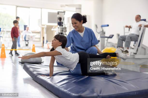 happy girl doing stretching exercises with the help of her physiotherapist - sports physiotherapy stock pictures, royalty-free photos & images