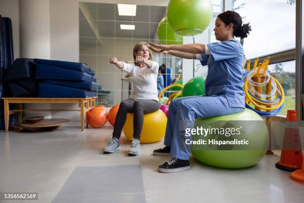 physical therapist showing a woman an exercise for her recovery - orthopaedic equipment imagens e fotografias de stock