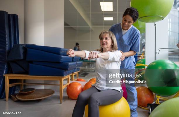 therapeutin hilft einer älteren frau bei ihrer physiotherapie in einem reha-zentrum - sportmedizin happy stock-fotos und bilder