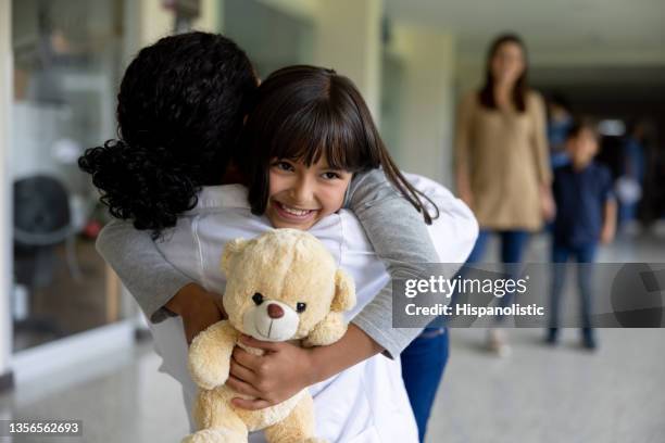 happy girl hugging her doctor at the hospital - doctors embracing stock pictures, royalty-free photos & images