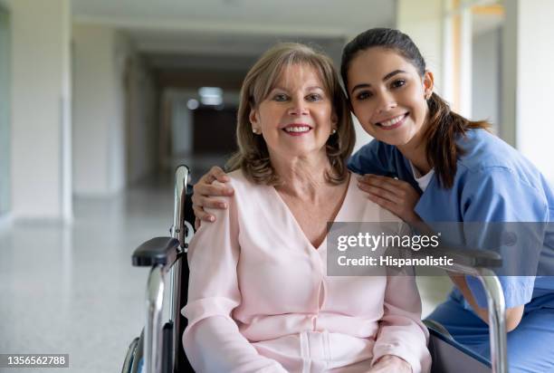 happy nurse smiling with a female patient in a wheelchair at the hospital - nurse leaving stock pictures, royalty-free photos & images