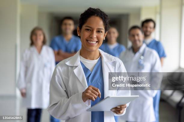 glücklicher arzt, der ein team von mitarbeitern des gesundheitswesens im krankenhaus leitet - arzt stock-fotos und bilder