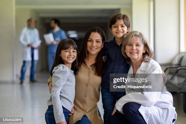 happy family smiling at the hospital with a doctor - family with doctor stock pictures, royalty-free photos & images