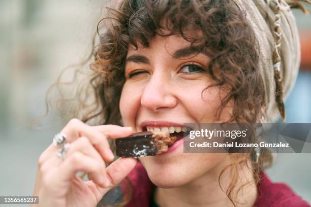 cheerful woman eating candy on street - snacking stockfoto's en -beelden