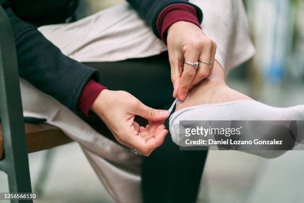 unrecognizable woman applying band aid on heel - applying plaster stock pictures, royalty-free photos & images